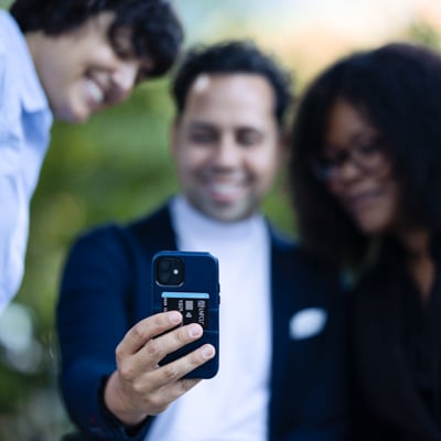 Three individuals looking at cellphone.