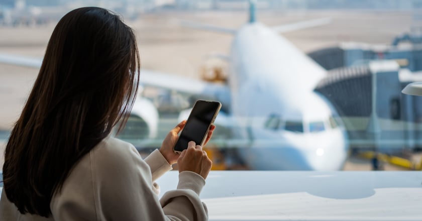 Individual looking at cellphone at the airport.