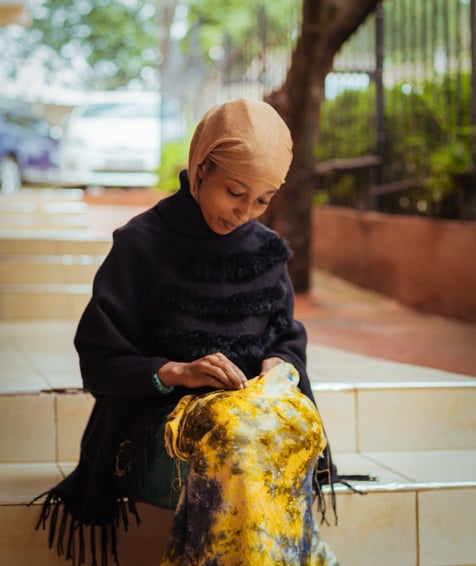 Individual sewing outdoors at RefuShe.