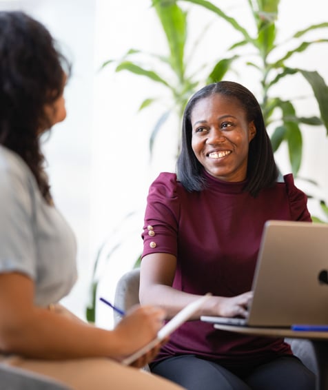 Two UNFCU staff members collaborating in front of a laptop.