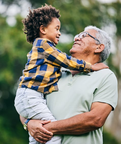 Individual embracing their grandchild outdoors.