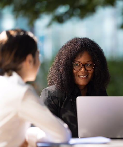 Two UNFCU staff collaborating in front of a laptop outdoors.