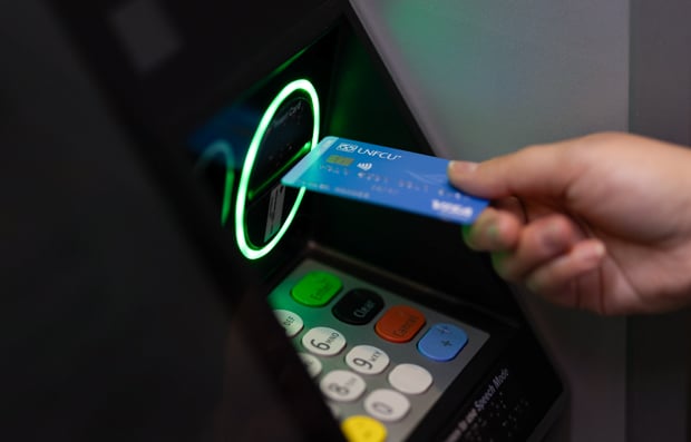 Individual using UNFCU Azure credit card at an ATM.