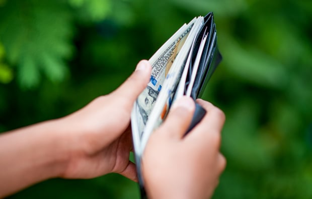 Individual holding wallet with cash.