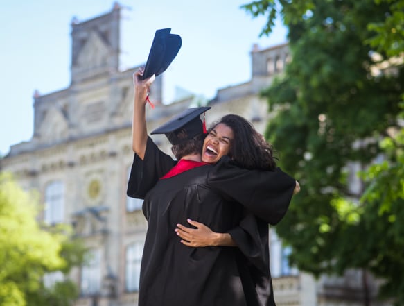 Two individuals embracing in graduation clothing.