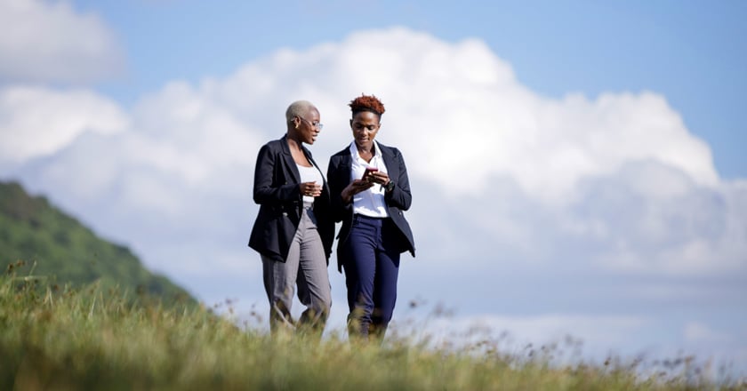 Two individuals walking on a hill.