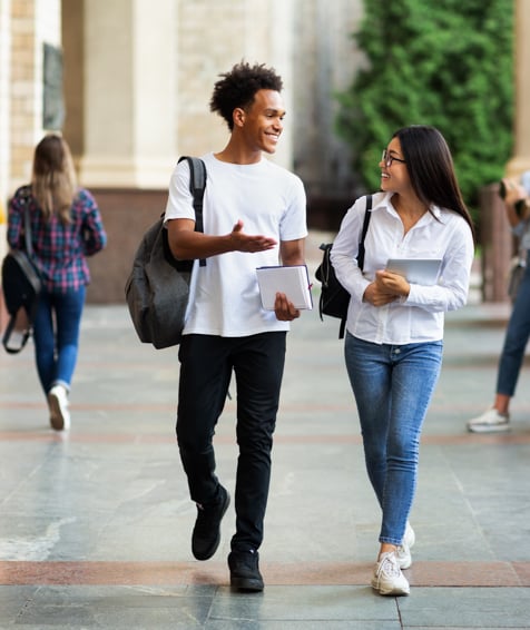 Two individuals walking across university campus.