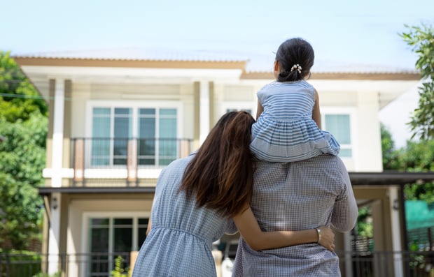 Two individuals and their child looking at their home.