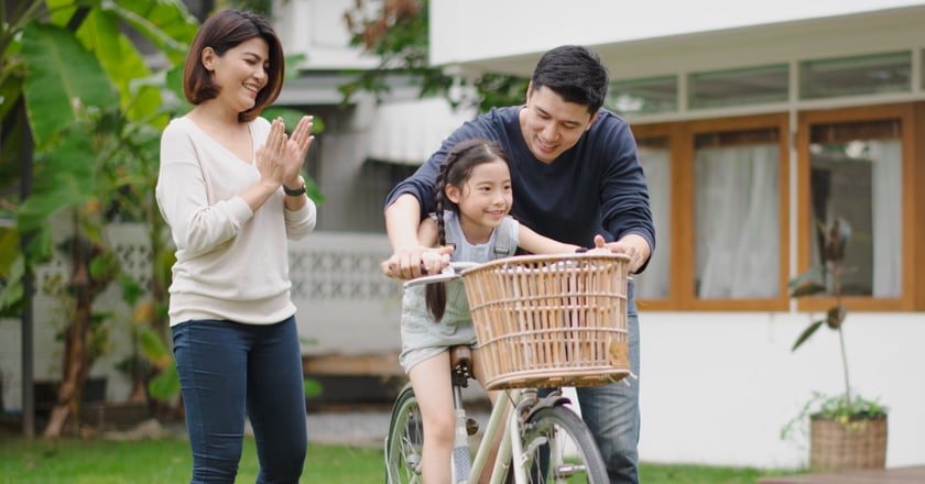 Two individuals and their child playing in their back yard.